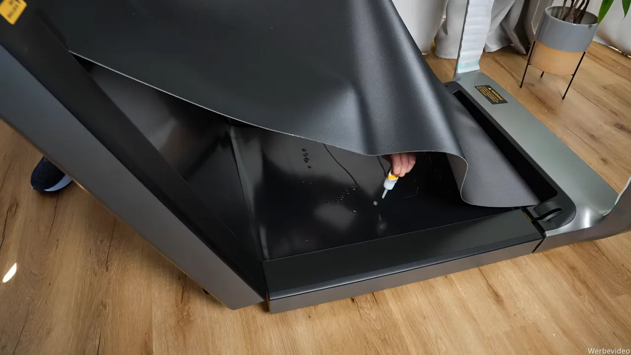 Hand trägt Silikonöl unter die Lauffläche des WalkingPad X218 auf