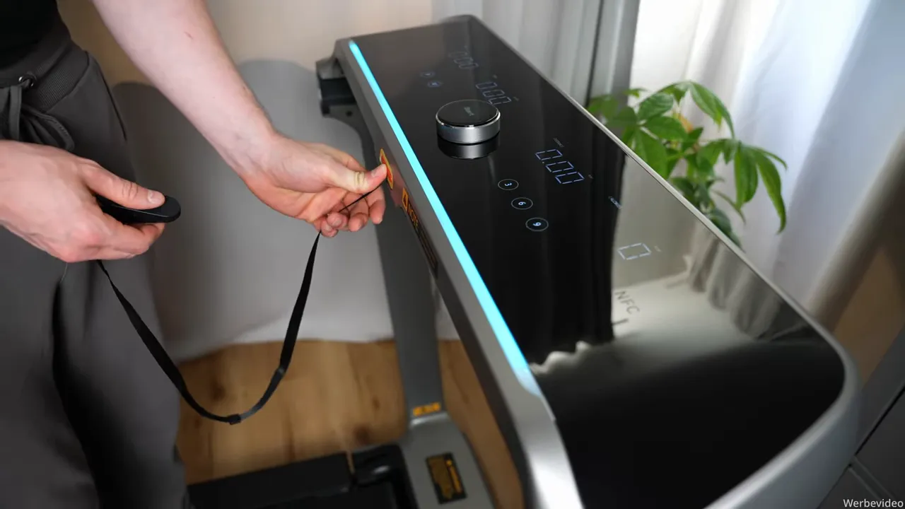 Hand steckt Sicherheitsstecker (Notstopp-Leine) in das Display des WalkingPad X218