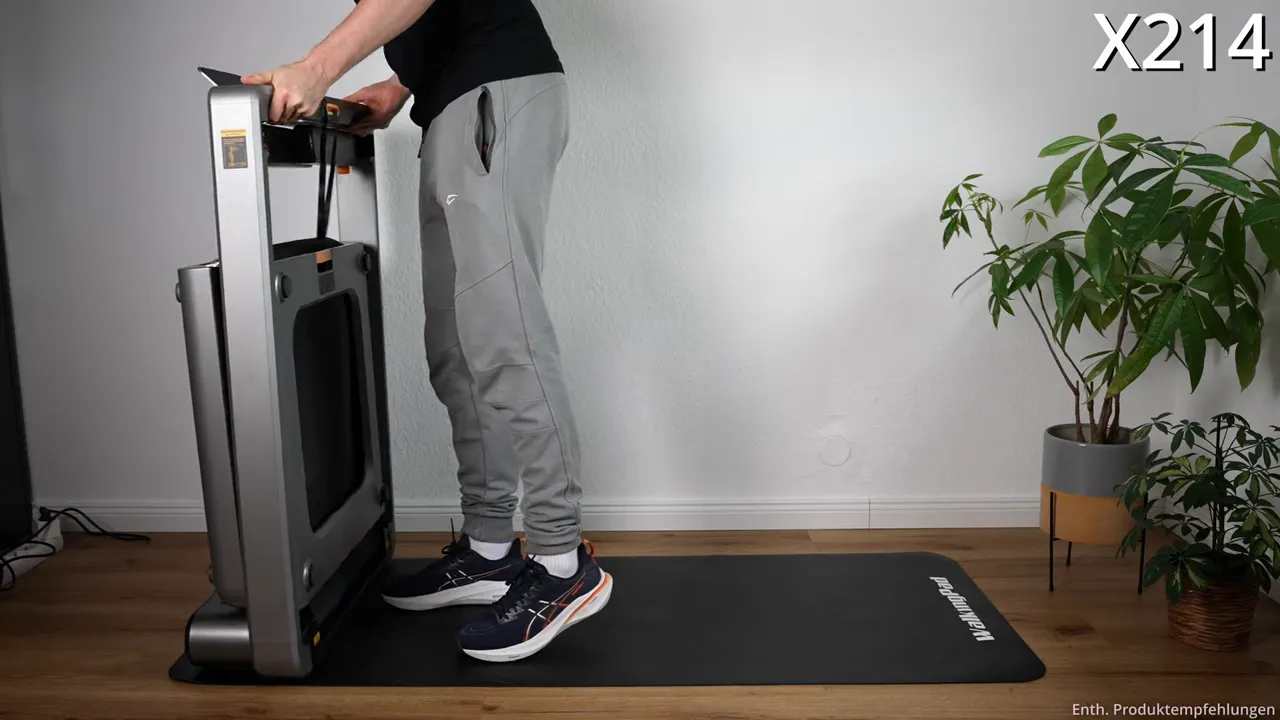 WalkingPad X214 aufrecht zusammengeklappt neben Pflanzen auf Matte, Aufnahme zeigt Lagerposition und Handhabung