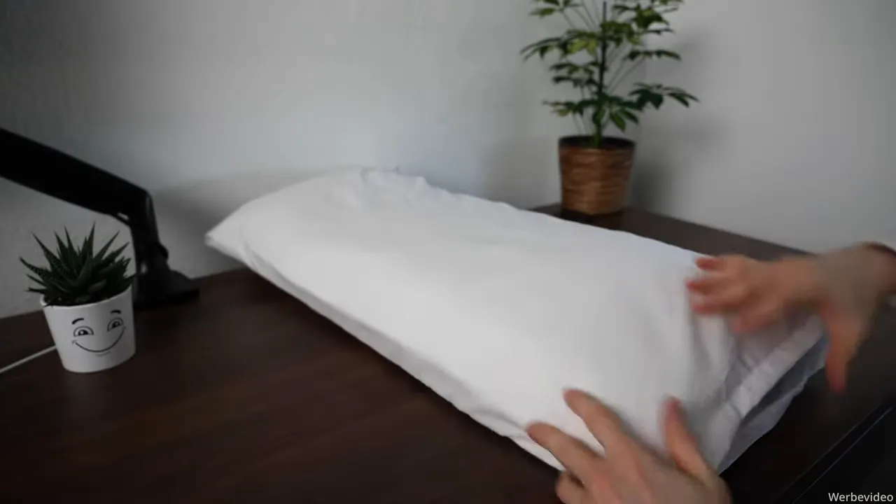 Hände prüfen die Kissennaht und die Oberfläche des Kissens, sauber verarbeitete Kanten sichtbar