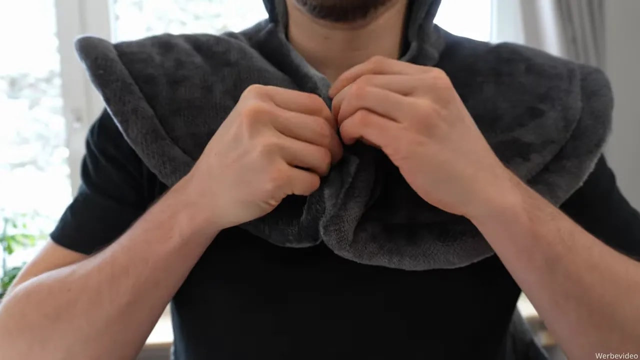 Heizdecke für Rücken, Schulter & Nacken von Bob & Brad im Test 5 Nahaufnahme: Hände befestigen die Druckknöpfe der Heizdecke am Nacken