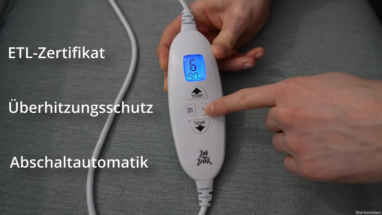 Heizdecke für Rücken, Schulter & Nacken von Bob & Brad im Test 8 Nahaufnahme des Bob & Brad Controllers mit blauem Display, Finger bedient die Timer‑Taste