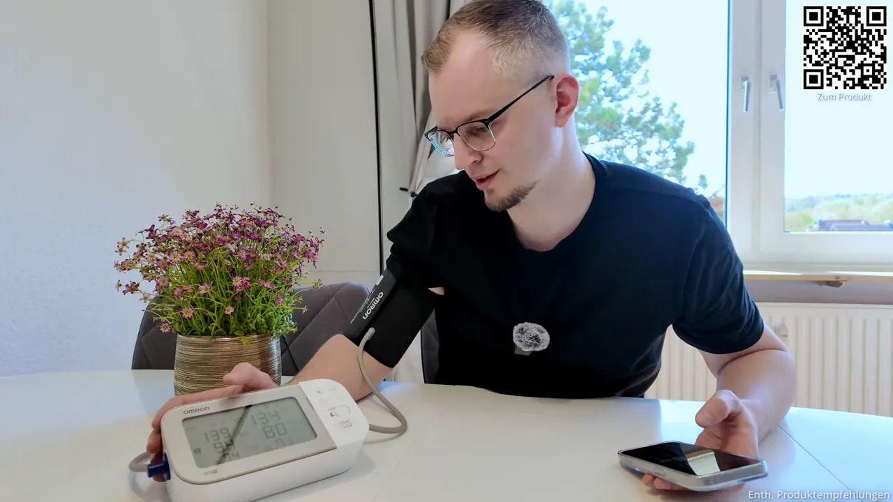 Person hält das Display des OMRON X7 Smart während der Blutdruckmessung und betrachtet die Werte