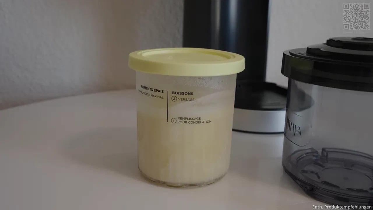 Gefrorener Behälter mit heller Eisbasis neben Außenschüssel und Gerät