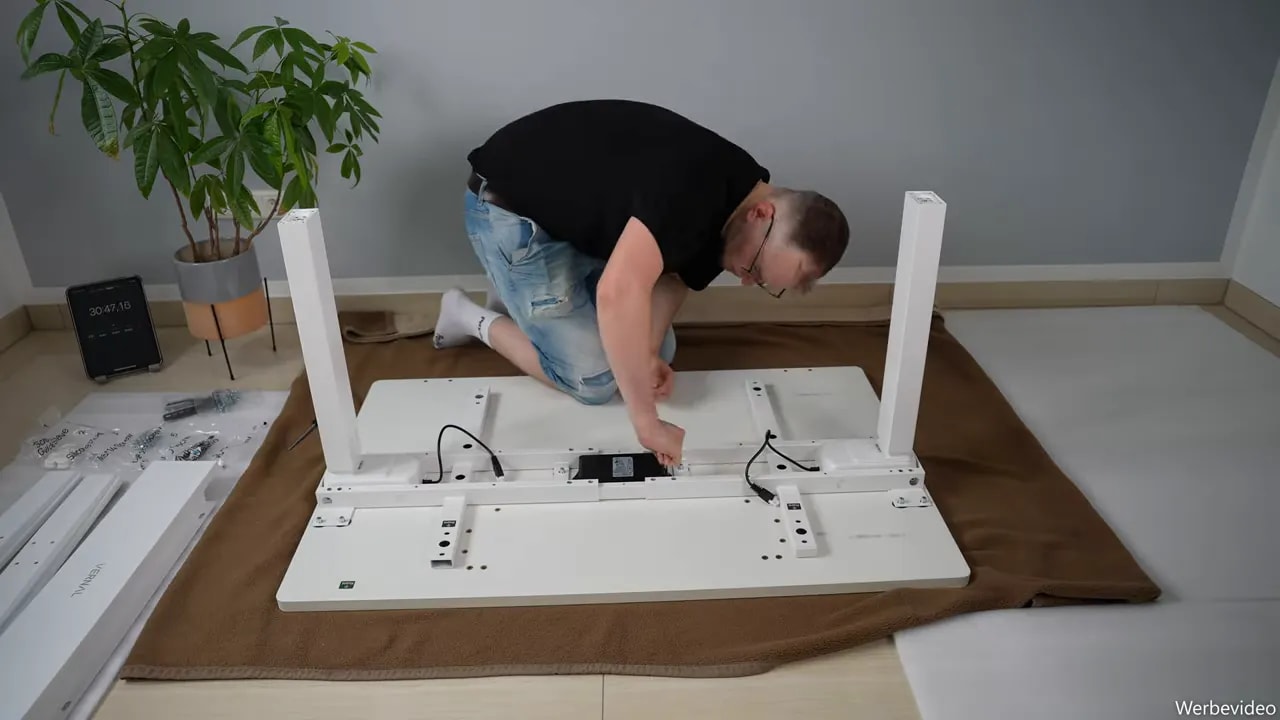 Underside of the assembled desk with lifting columns, control box and routed cables