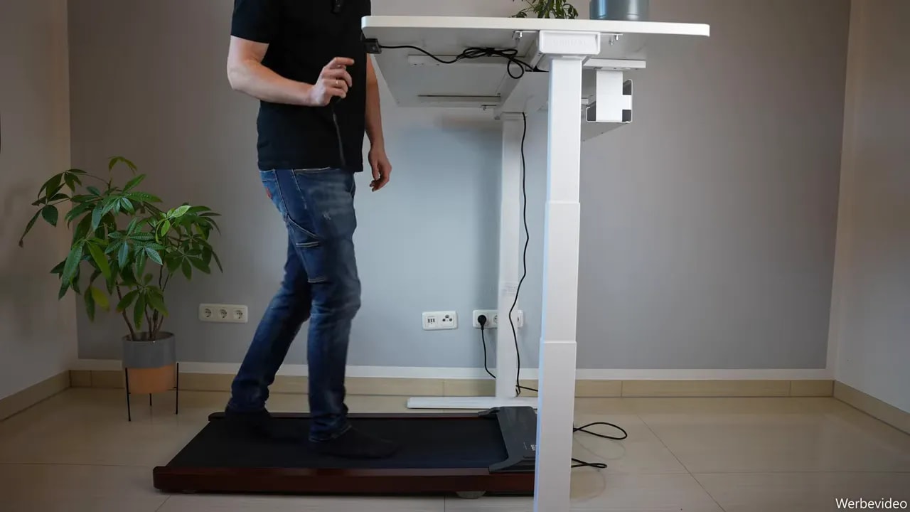Person walking on a walking pad at a tall white desk