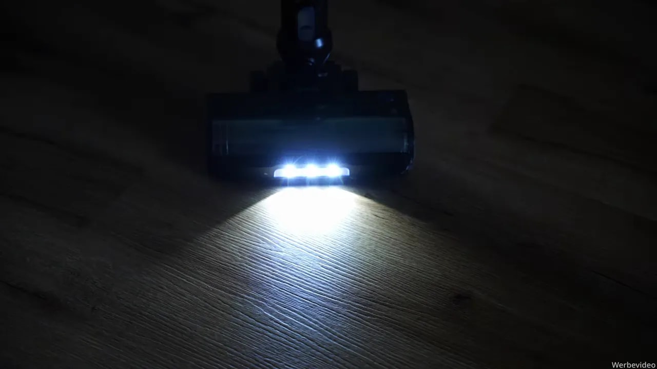 Helle LED-Leuchten an der Bodendüse beleuchten einen Holzboden im dunklen Raum