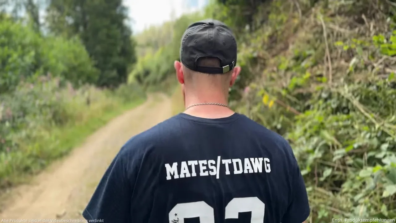 Person von hinten auf einem schmalen Weg zwischen grünen Böschungen