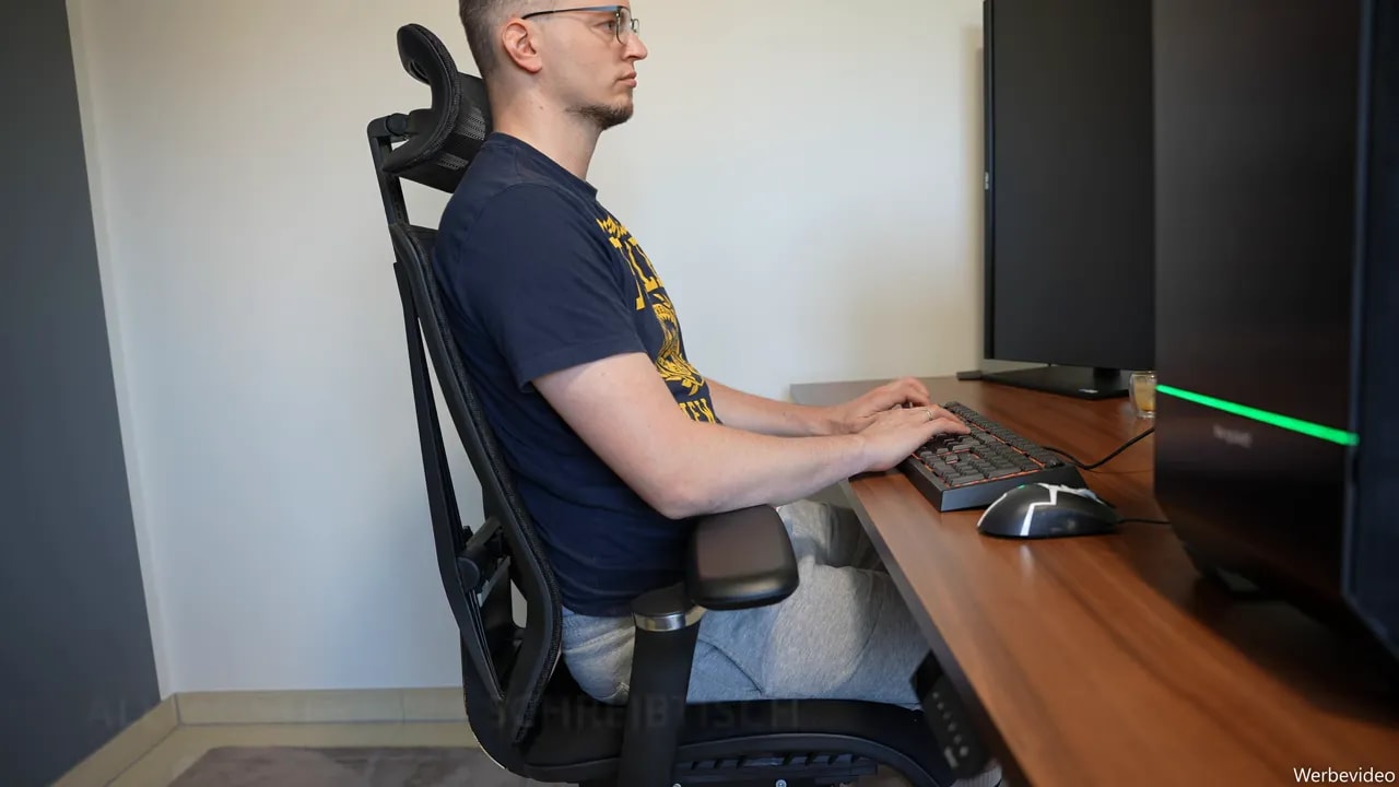 Person arbeitet auf dem VALKENSTOL M8 an einem Schreibtisch mit Tastatur und Monitoren