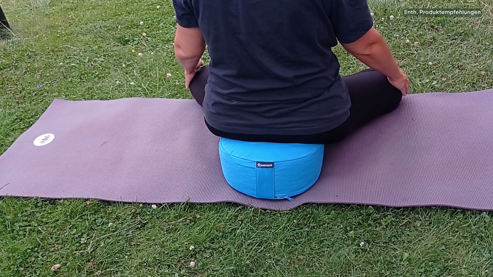 Person sitzt auf dem BODYMATE Yogakissen auf einer Yogamatte