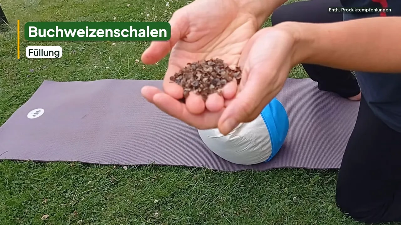 Hände zeigen Buchweizenschalen vor dem geöffneten Innenkissen auf einer Yogamatte