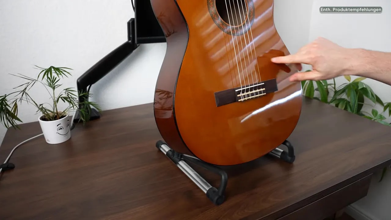 Konzertgitarre auf den beiden unteren Auflagen des silbernen Gitarrenständers