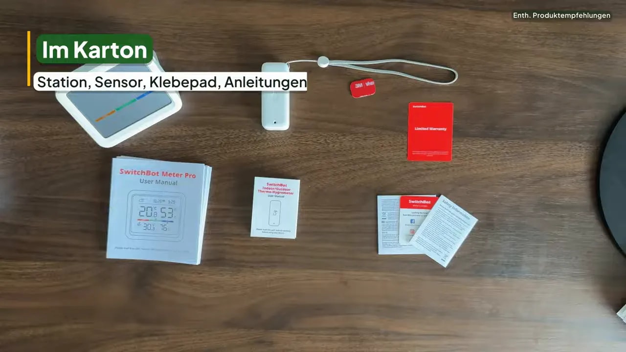 Innenstation, Außensensor mit Schlaufe, Klebepad und Anleitungen auf einem Holztisch